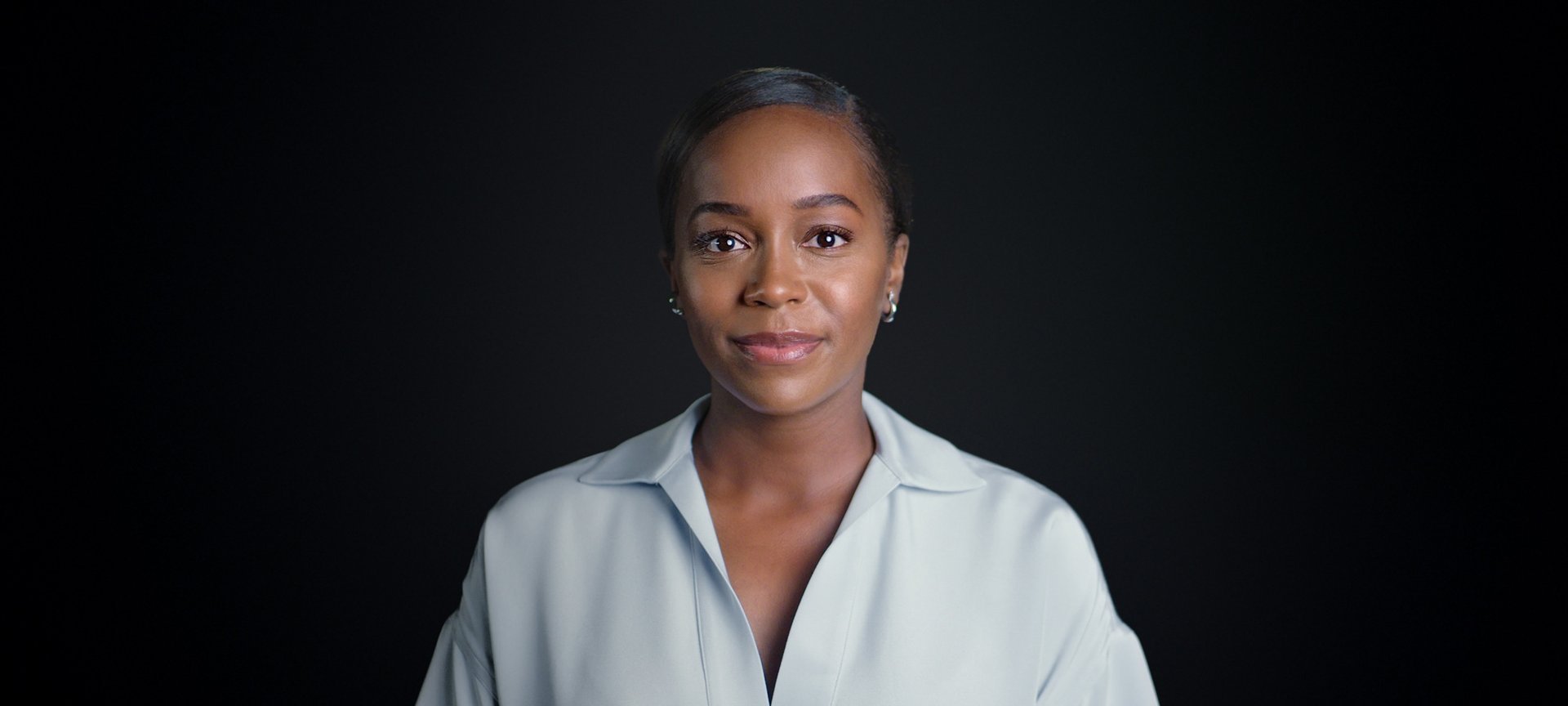 Portrait photo of Aja Naomi King in front of black background.