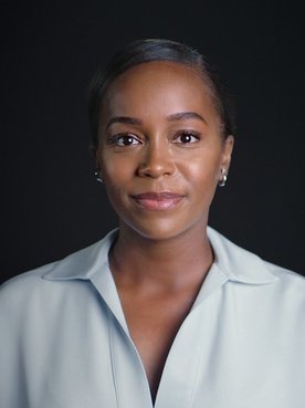 Portrait photo of Aja Naomi King in front of black background.