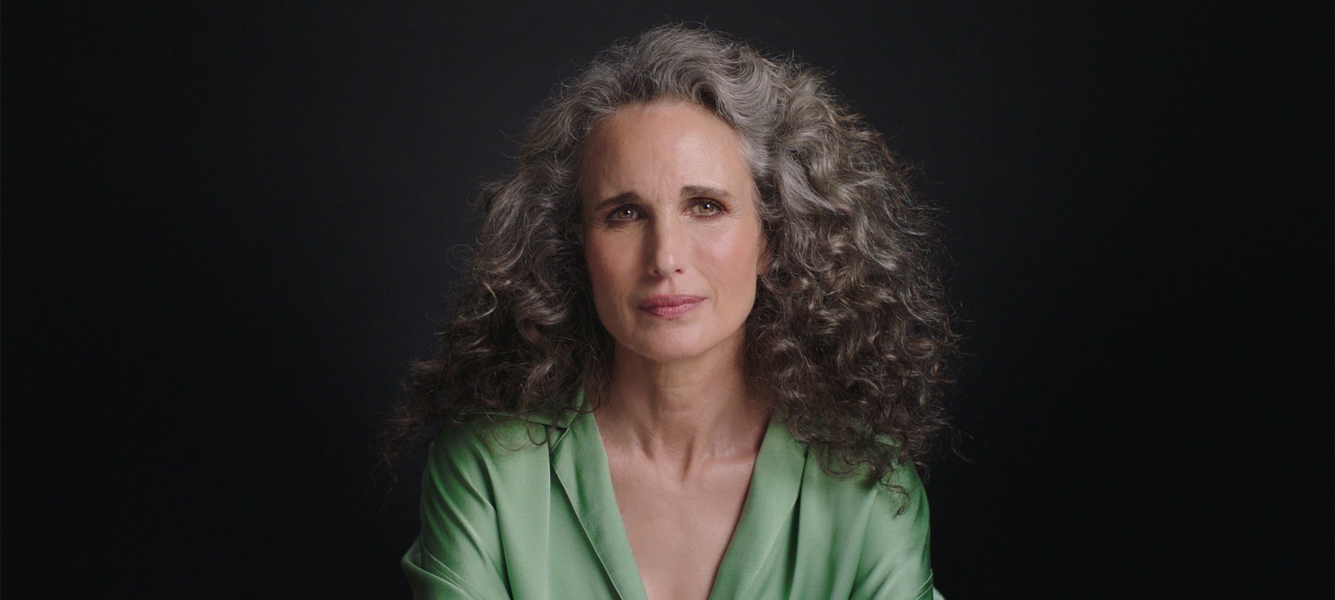 Portrait photo of Andie MacDowell in front of black background.