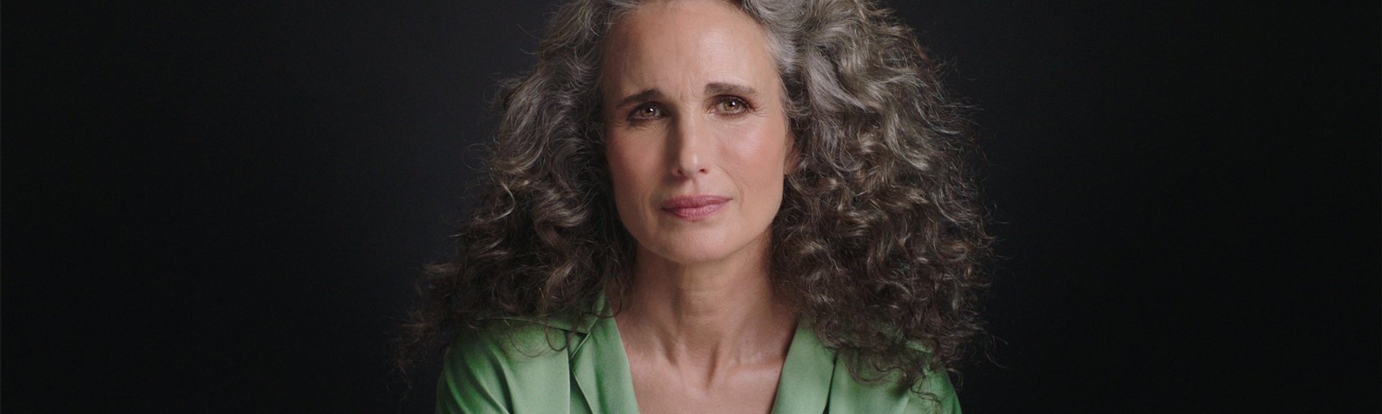 Portrait photo of Andie MacDowell in front of black background.