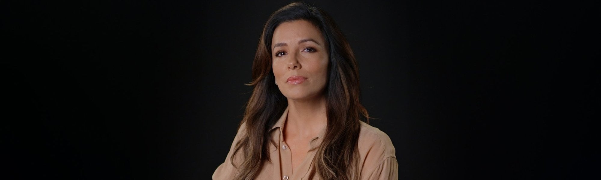 Portrait photo of Eva Longoria in front of black background.